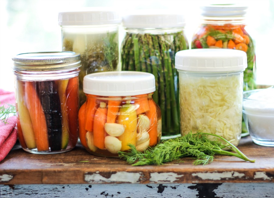 a row of jars lined up with different veggies inside