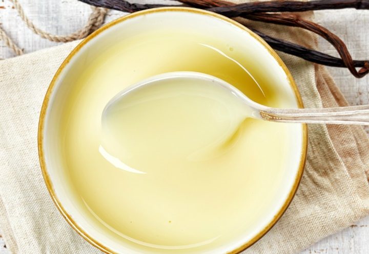 bowl of vanilla custard that's dairy-free on white wooden table, top view