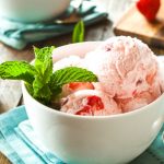white bowl with blender strawberry ice cream scoops and fresh mint