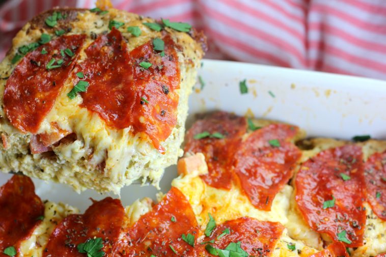 lifting out a slice of keto pizza bake casserole for super bowl party meal