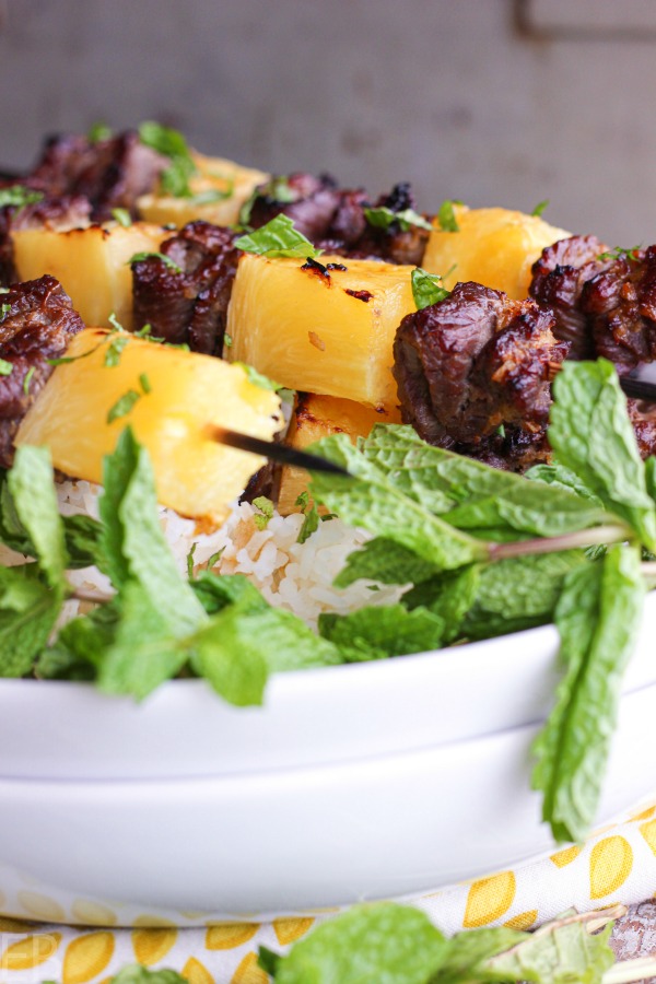 thai beef kabobs on white plates with fresh mint