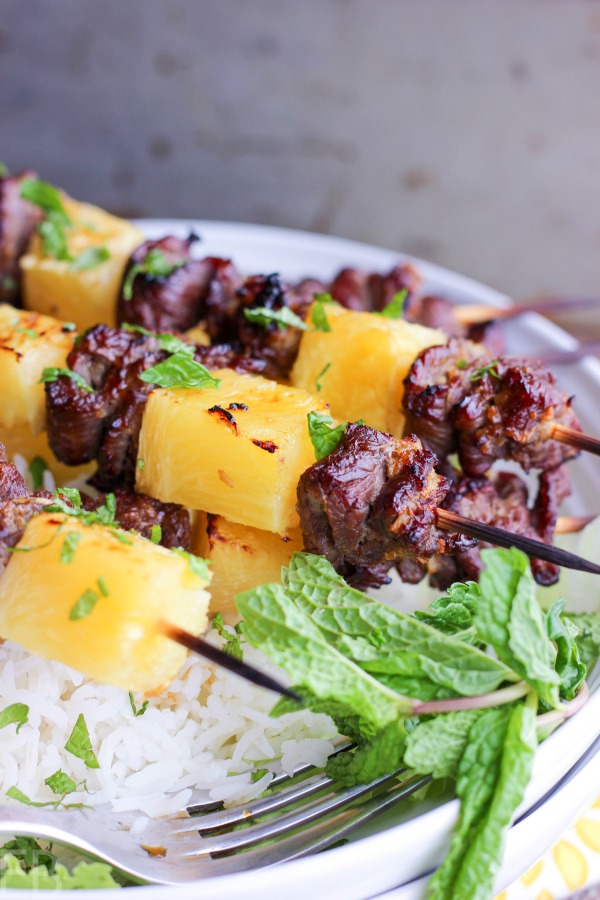 kabobs of beef sirloin and pineapple with fresh mint on white plate with rice