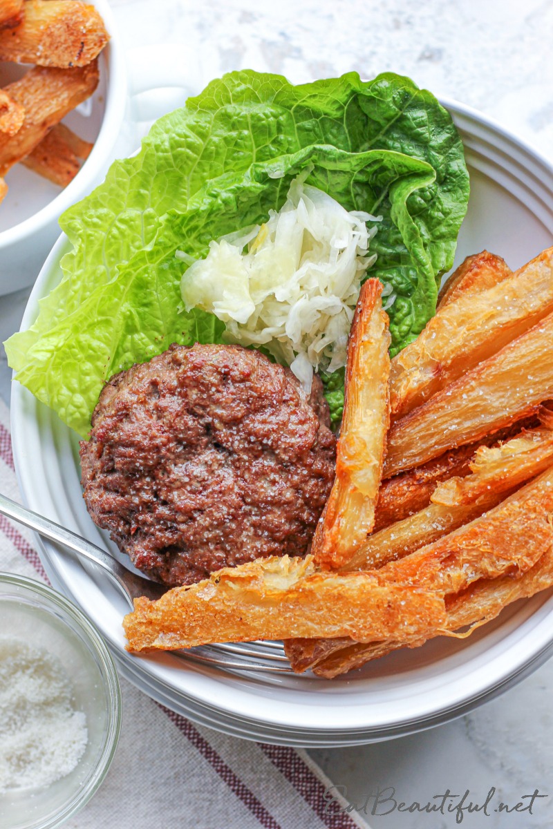 overhead view of aip burgers and fries in a white dish with lettuce and sauerkraut