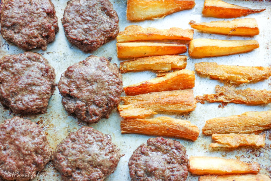 overhead view of a sheet pan with aip burgers and fries newly baked