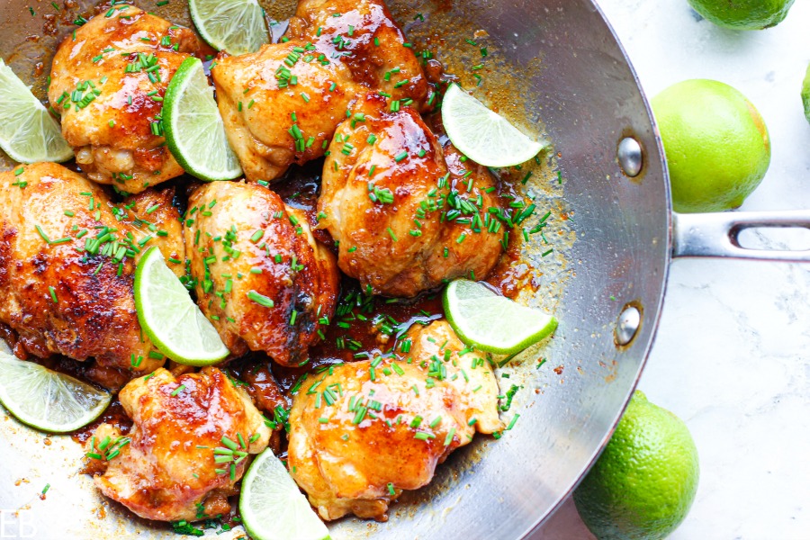 overhead view of pan with spicy honey lime chicken thighs and lime wedges