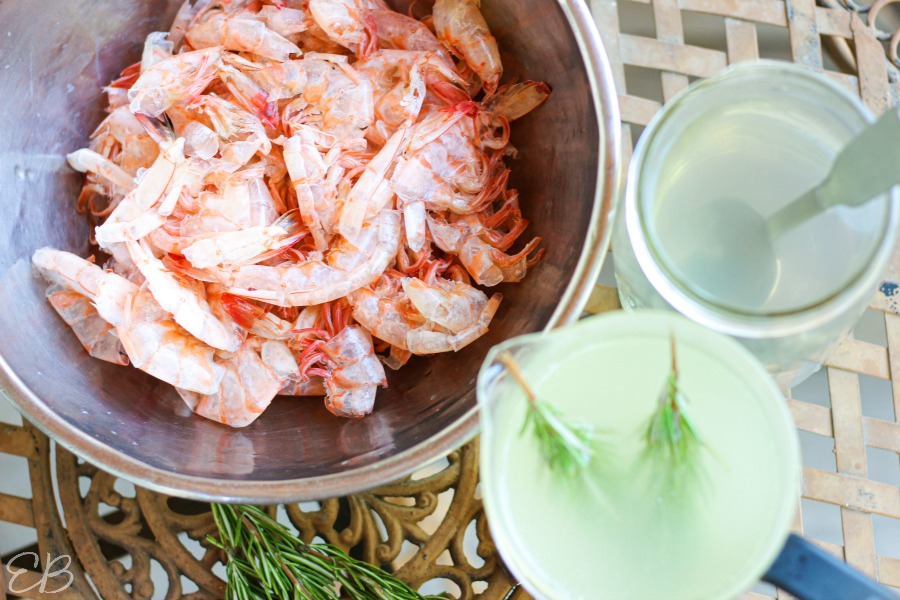 overhead view of cooked shrimp in bowl and shrimp stock with rosemary