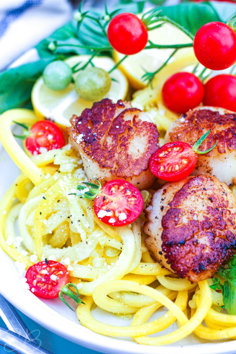 close up verticle image of scallop scampi with zoodles and tomatoes on the vine