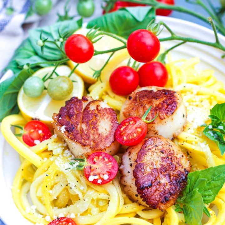 vertical image of scallop scampi with a branch of fresh tomatoes hanging over