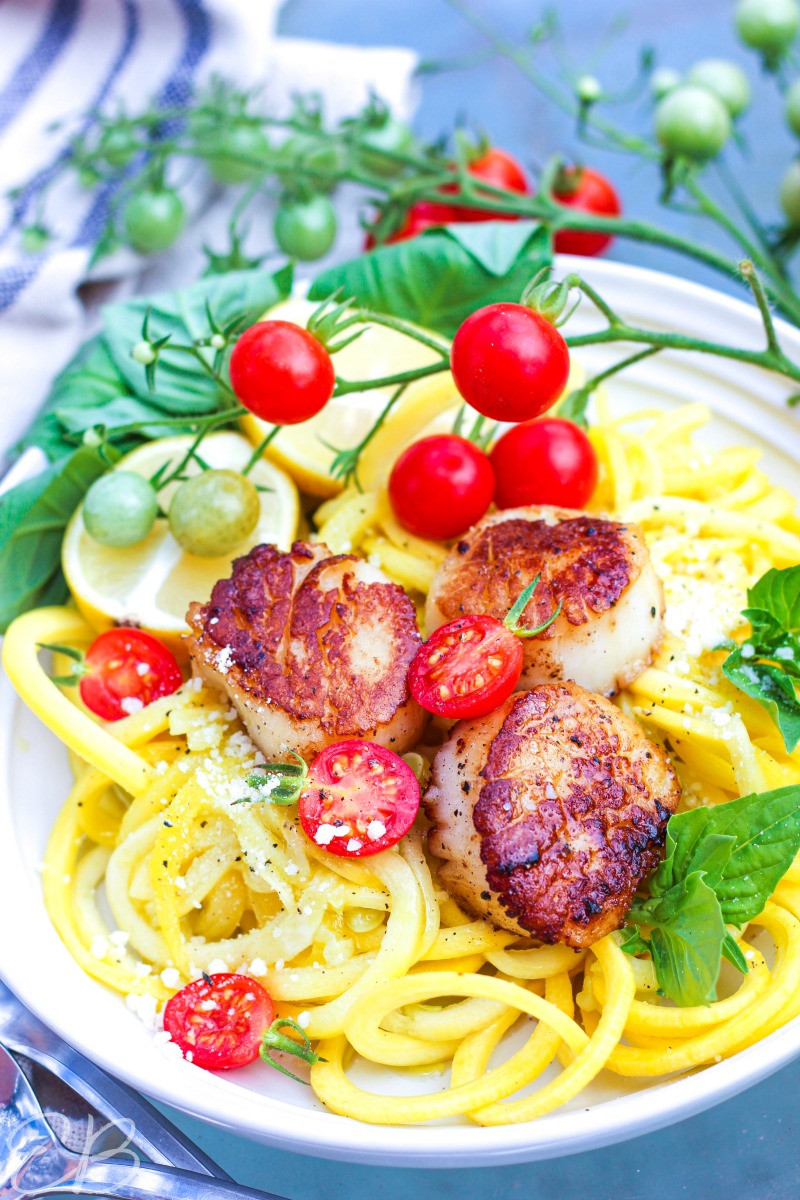 vertical image of scallop scampi with a branch of fresh tomatoes hanging over