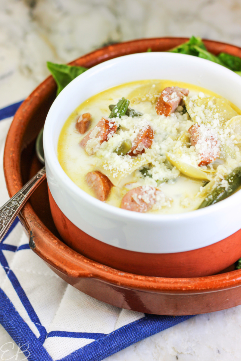 bowl of italian parmesan sausage soup soup with side salad and spoon