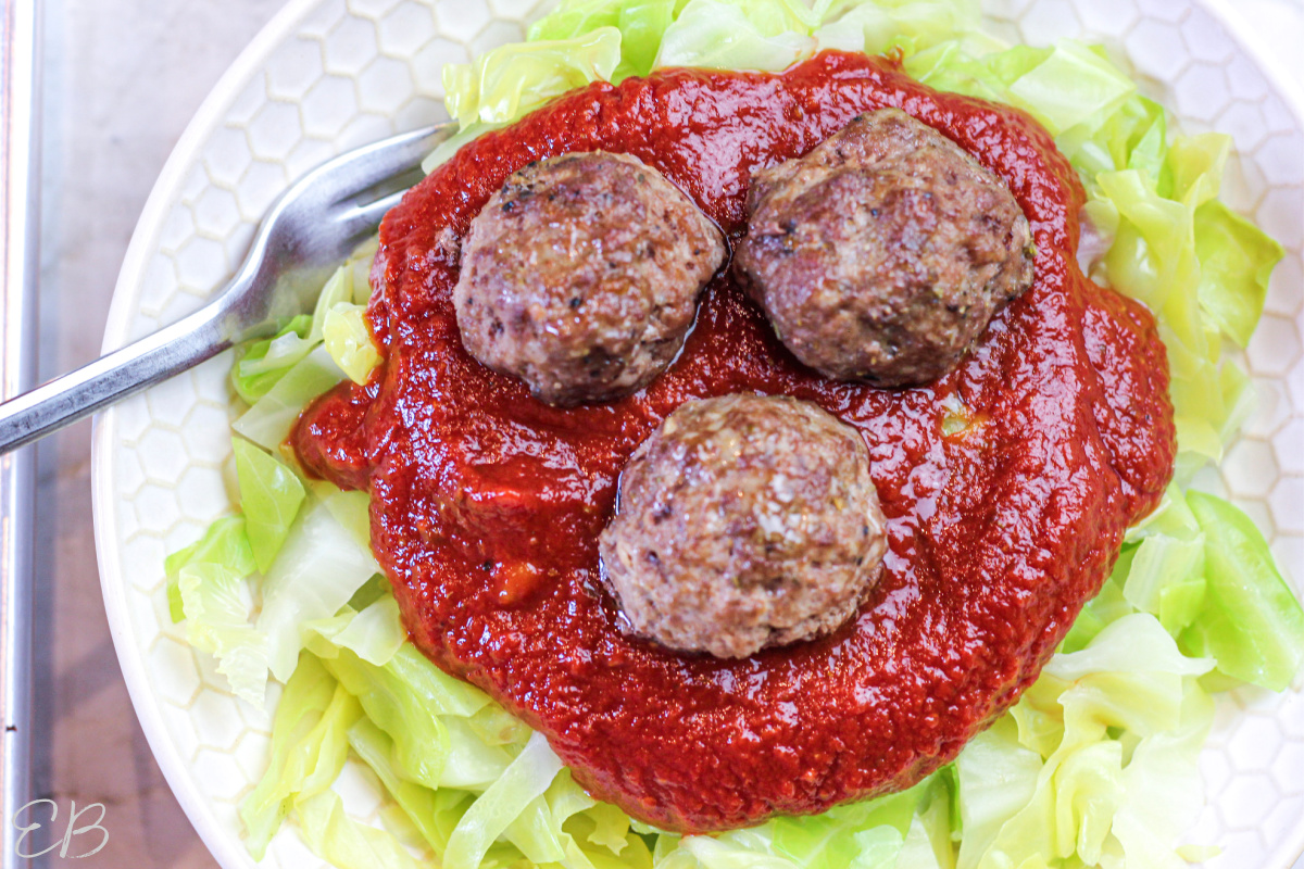 overhead view of cabbage noodles with sauce and meatballs