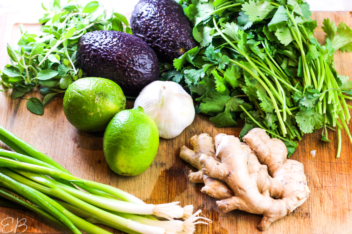 flavorful herbs and ingredients on a cutting board to be used for the stew, including cilantro and ginger