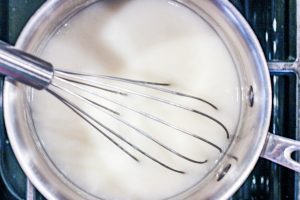 whisking oat milk with thickener over heat