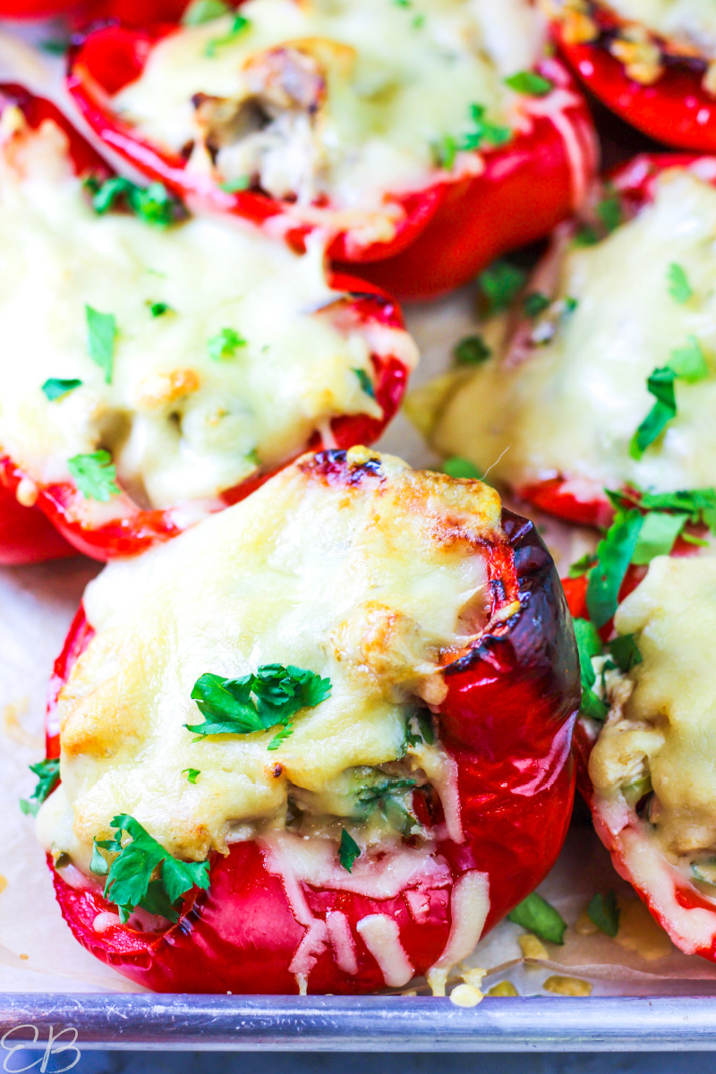 up close view of a red bell pepper stuffed with chicken and topped with cheese, in the baking pan