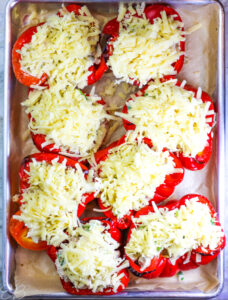 overhead view of red bell peppers stuffed with Mexican chicken and topped with cheese, just before baking