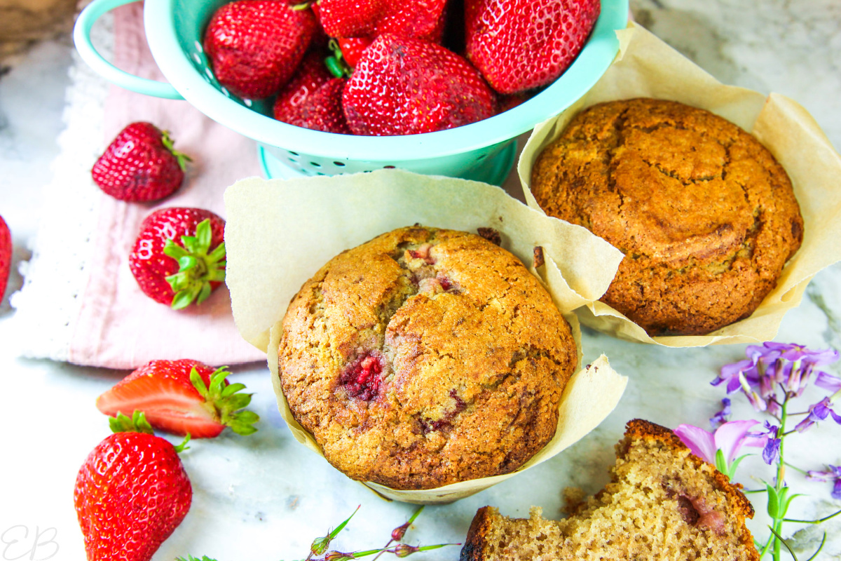 3 paleo strawberry muffins with fresh strawberries all around