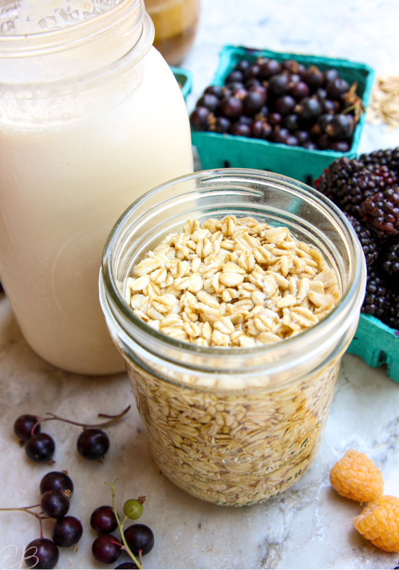 a jar of overnight oats in front of a bottle of milk and berries