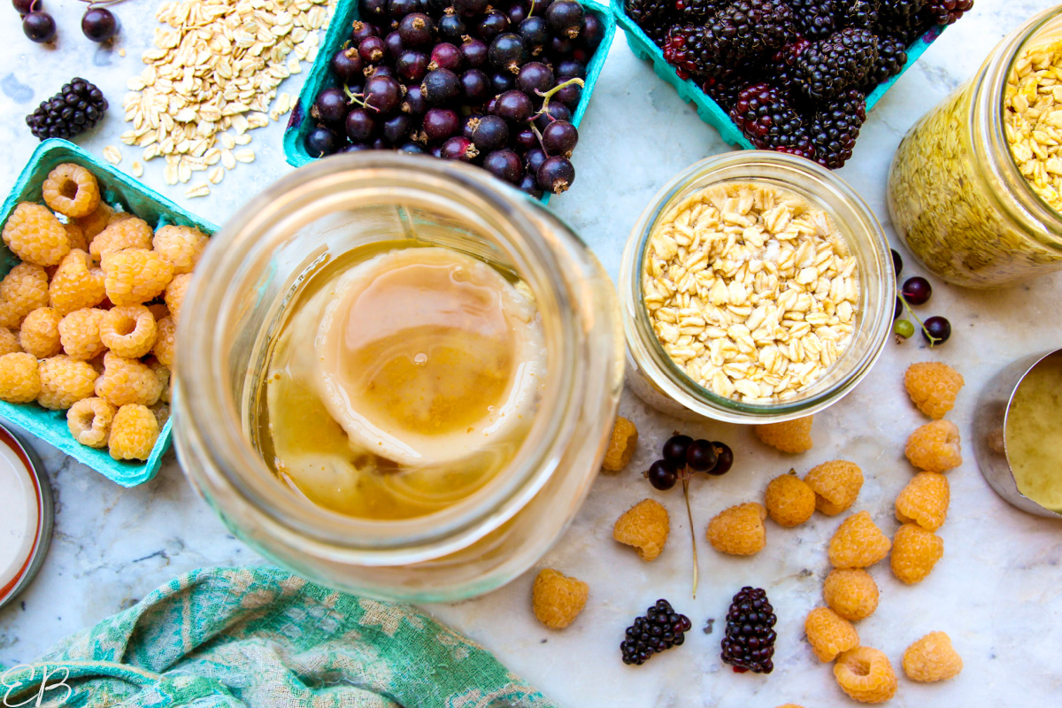 overhead view of homemade kombucha with the scoby plus jars of overnight oats and berries