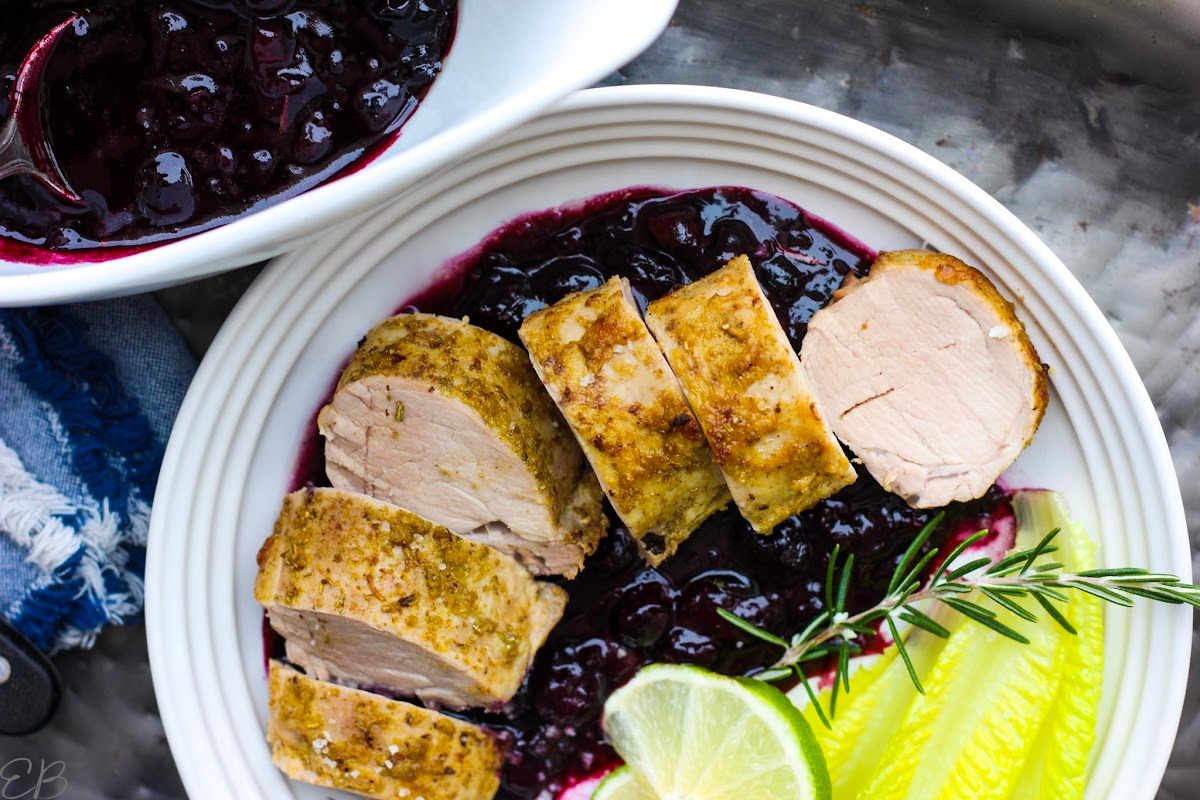 overhead view of sliced pork tenderloin on blueberry sauce