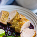 side angle view of sliced pork tenderloin with blueberry sauce