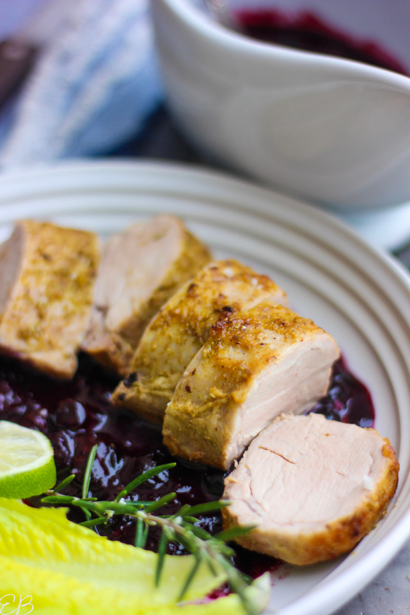 side angle view of sliced pork tenderloin with blueberry sauce