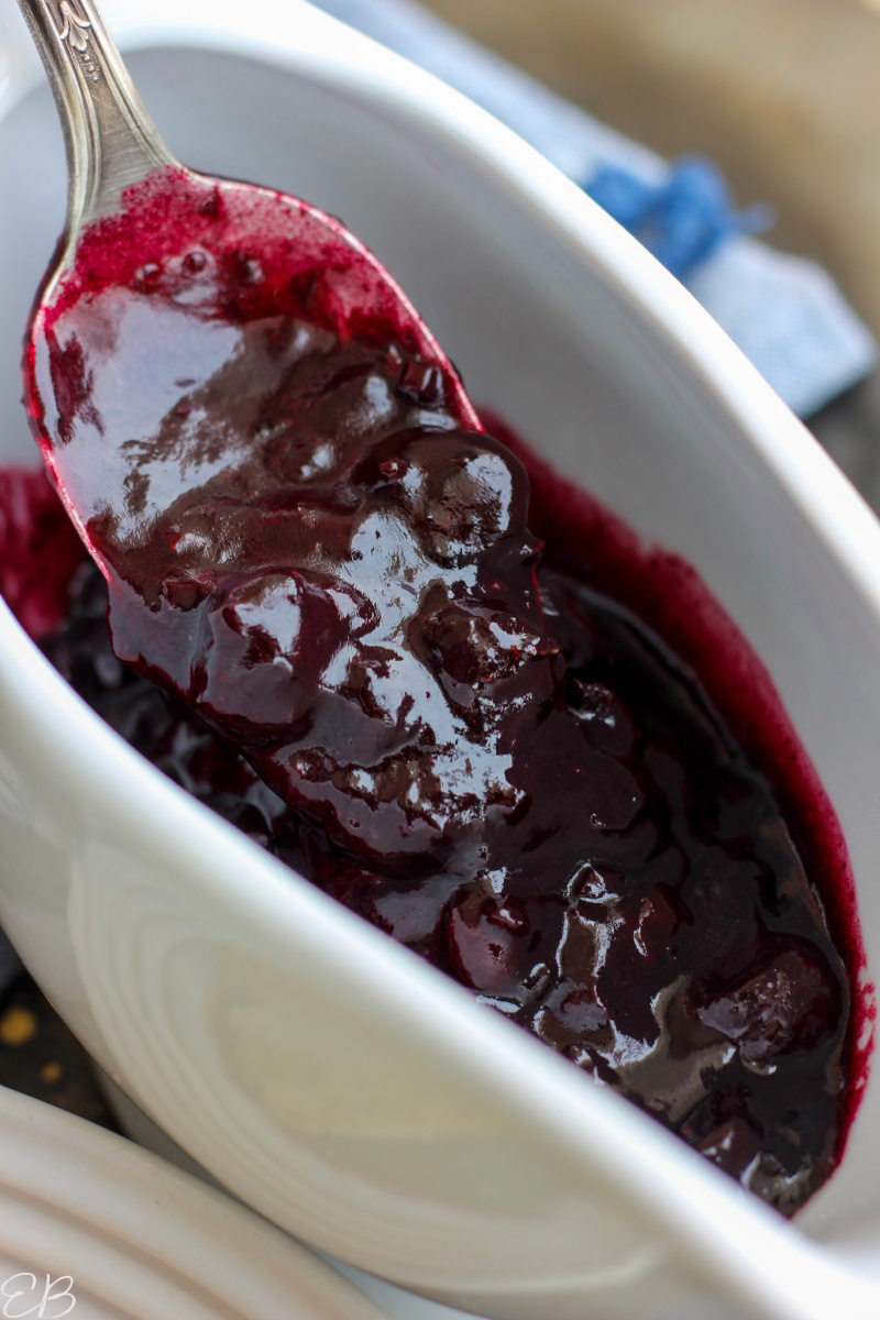 spoon in serving dish of blueberry sauce serving it and showing what it looks like