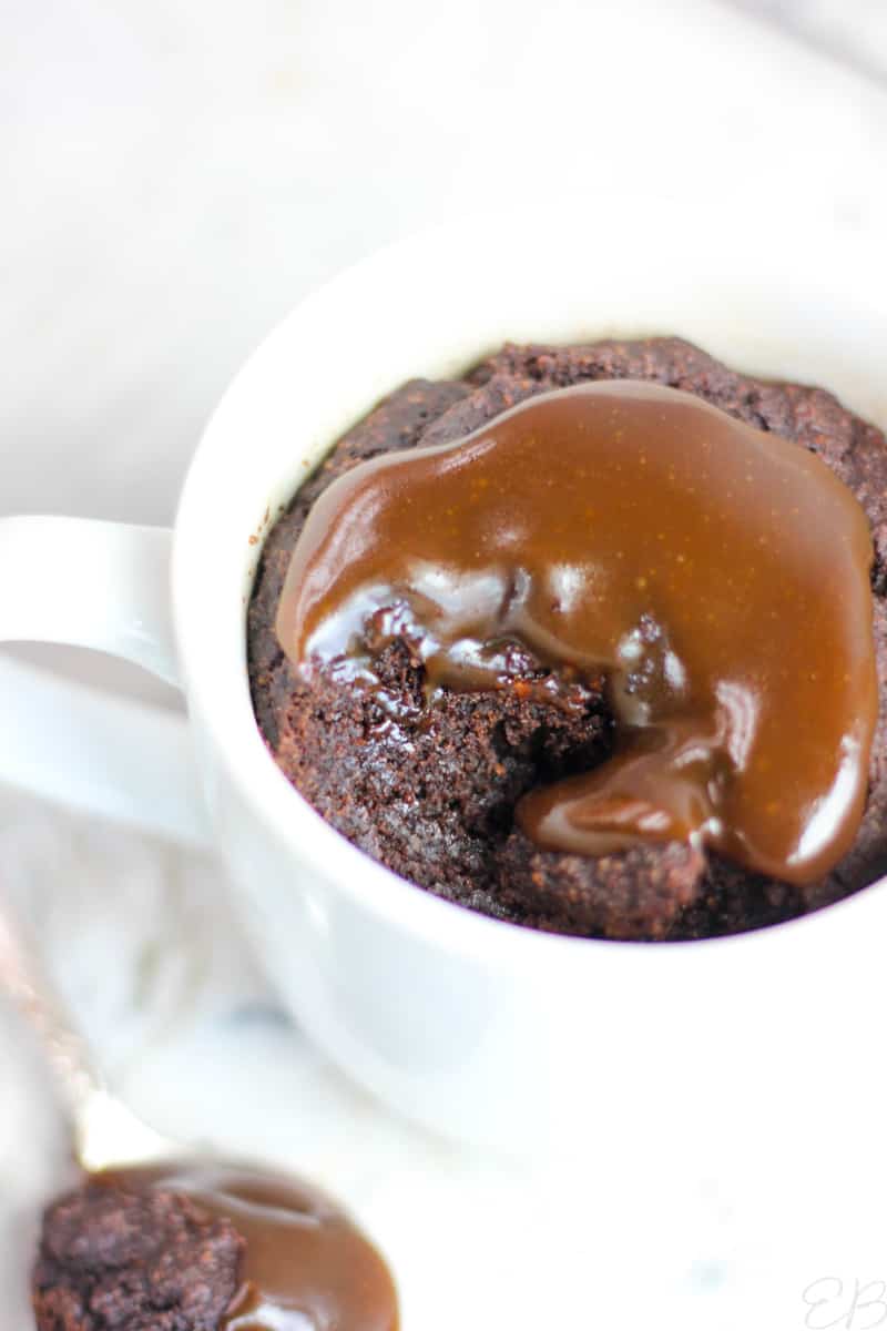 looking down into a mug with one bite out of it of paleo chocolate caramel mug cake