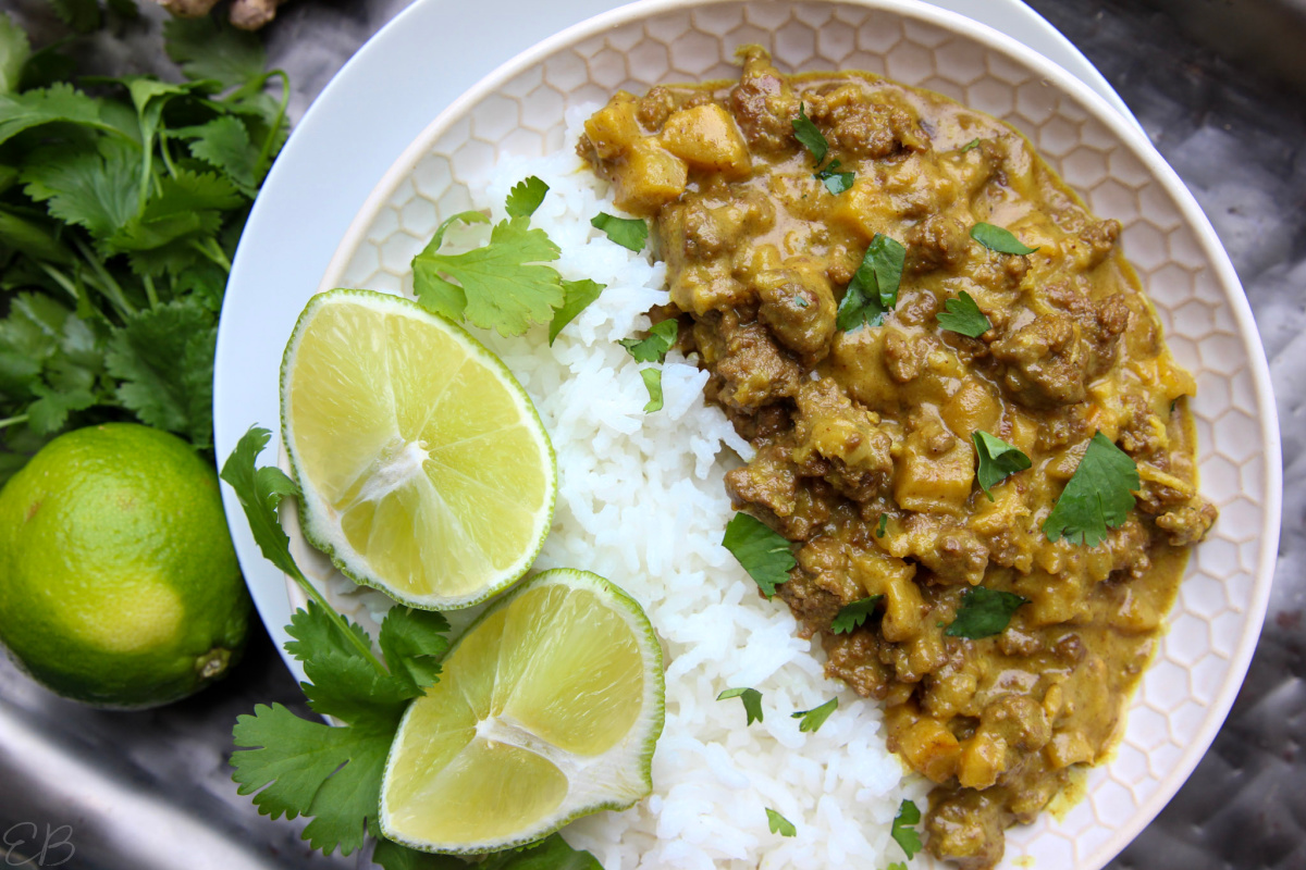 overhead view of paleo aip coconut ground beef curry with rice and limes