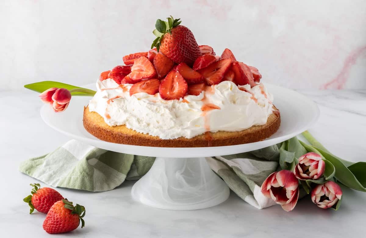 a strawberry cake topped with whipped cream and strawberries