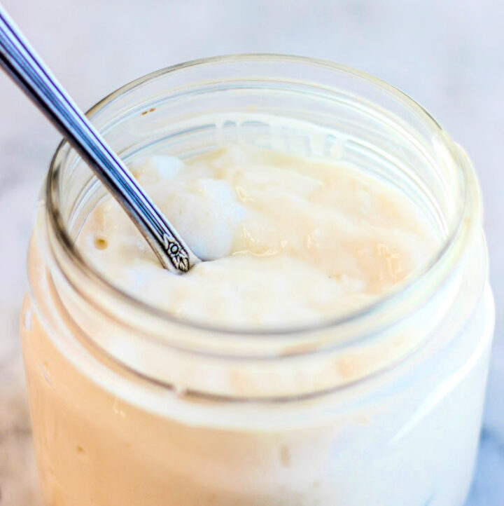 side angle view of mason jar with homemade coconut milk yogurt and spoon