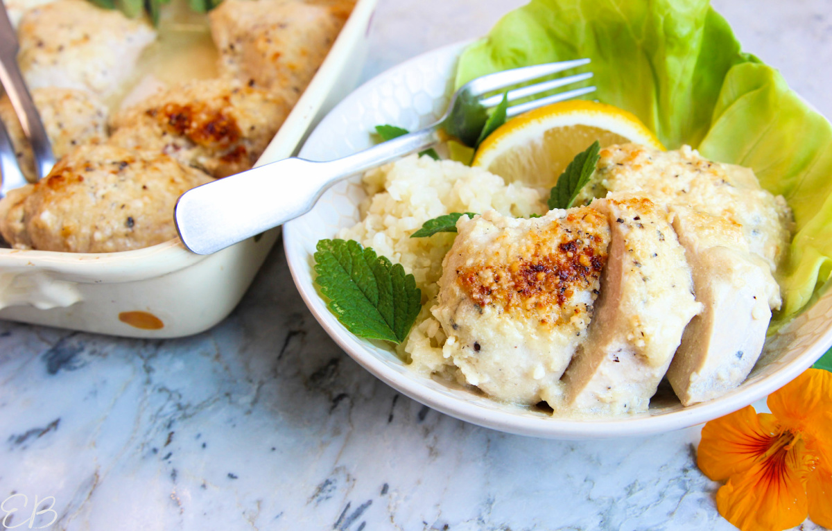 Sliced baked caesar chicken breast on white plate