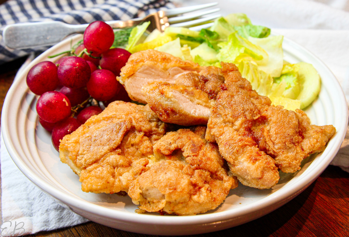 up close photo of paleo fried chicken served with a salad and grapes