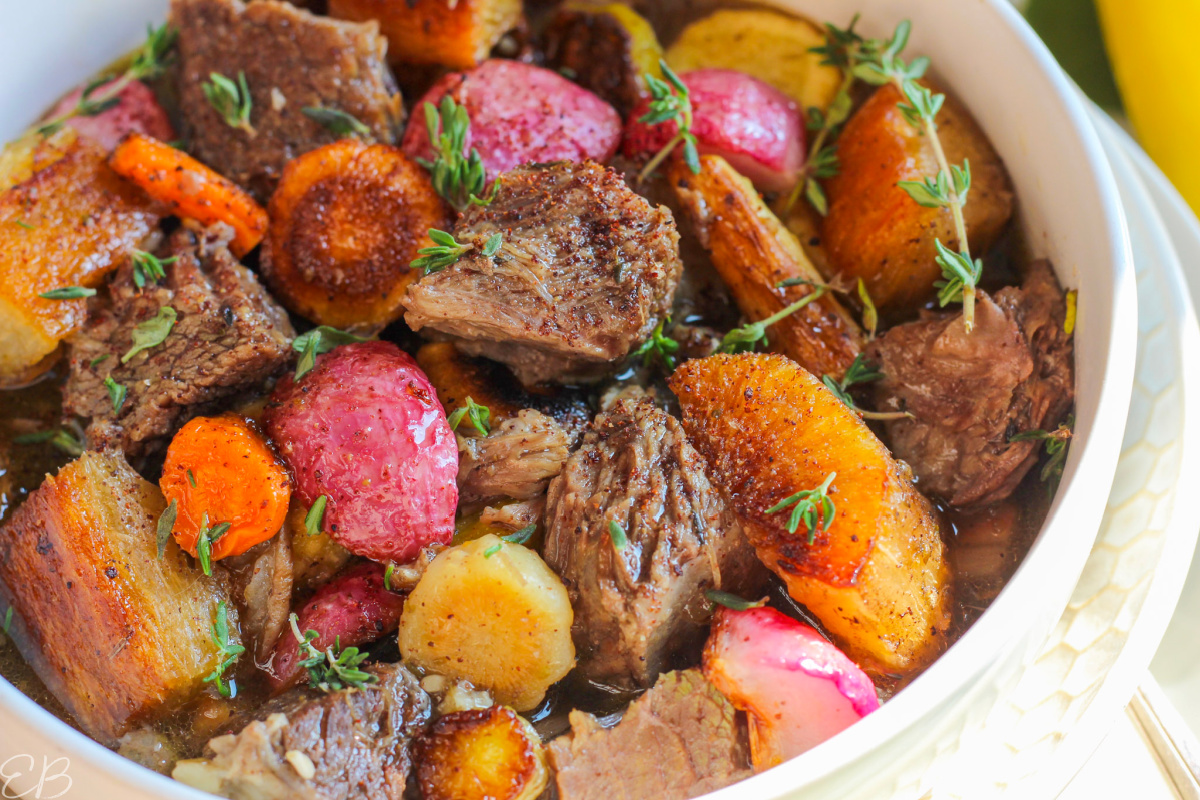 up close photo of beef stew with roasted veggies on top and sumac