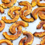 up close roasted delicata squash slices on a sheet pan