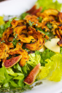 roasted delicata squash on top of lettuce greens