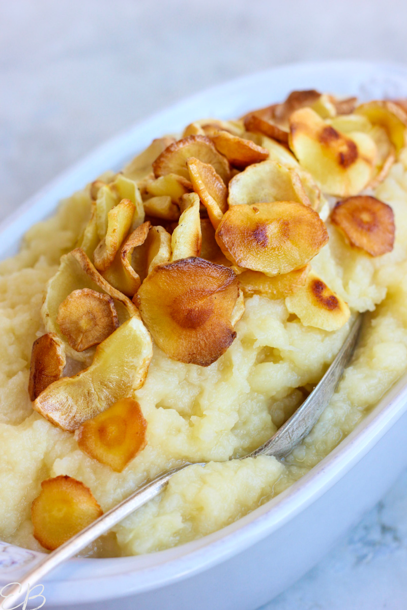up close serving parsnip puree gratin with silver spoon