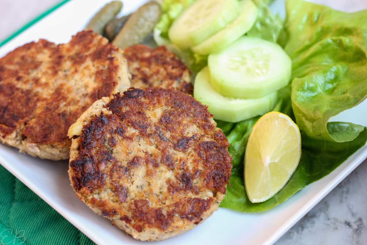 plate served with salmon patties, cucumbers and lime