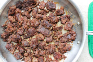 crispy beef flipped and cooking on its second side in pan