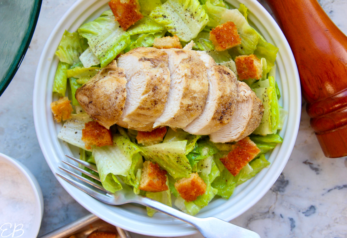 sliced chicken breast on top of anti-inflammatory caesar salad