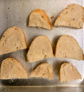 slices of bread being made into croutons on baking sheet