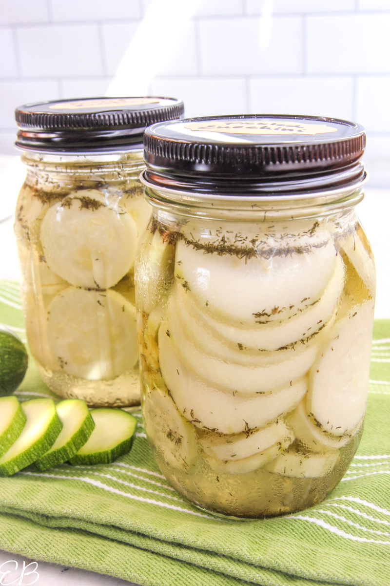 2 jars of pickled zucchini on green dish towel