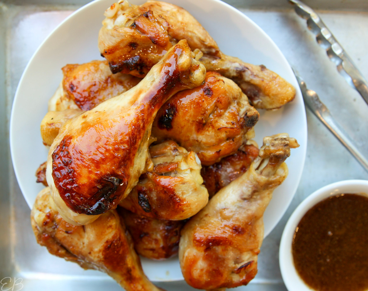 white serving bowl of paleo teriyaki chicken drumsticks, with sauce on the side