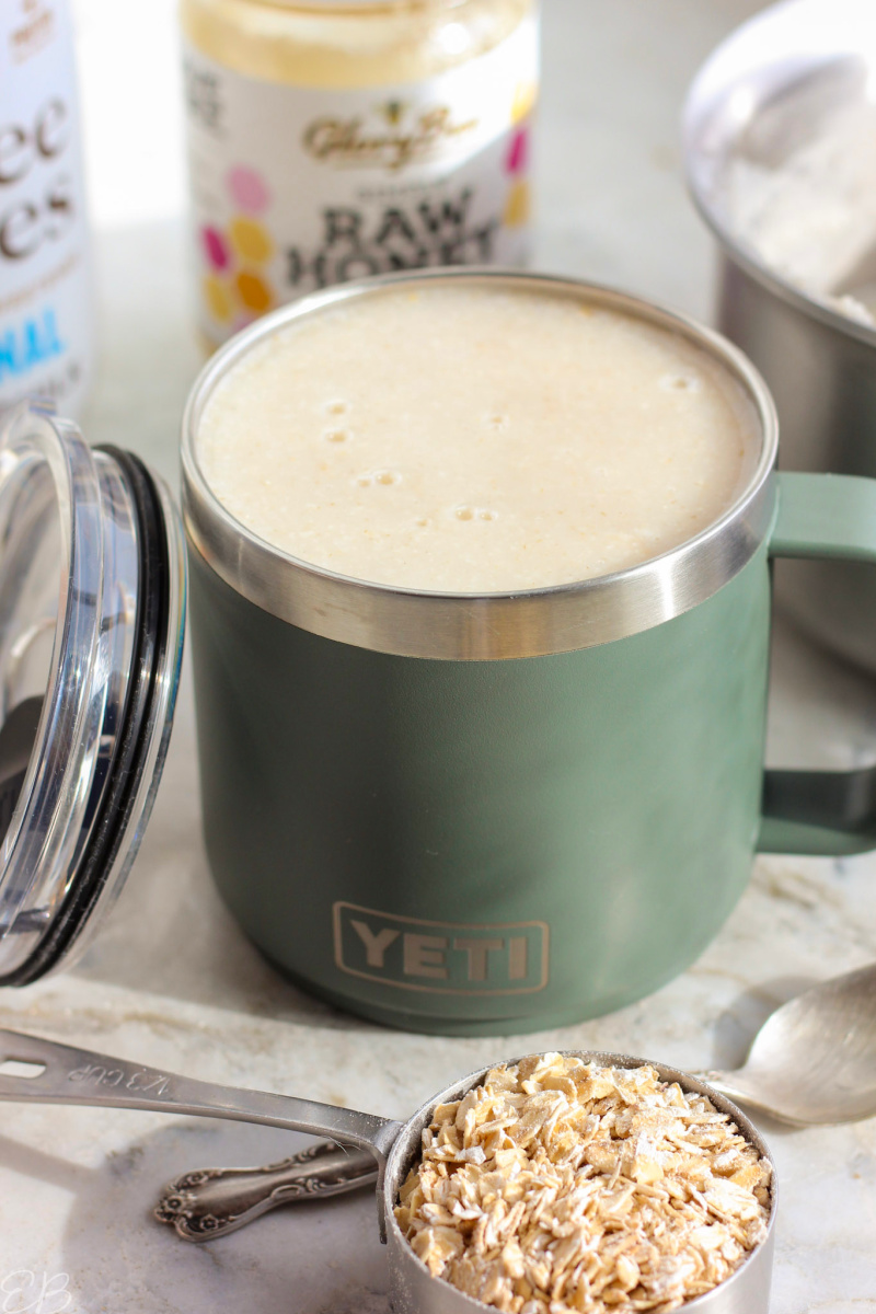 Drinkable Oatmeal Recipe in to-go mug surrounded by possible stir-ins and some rolled oats