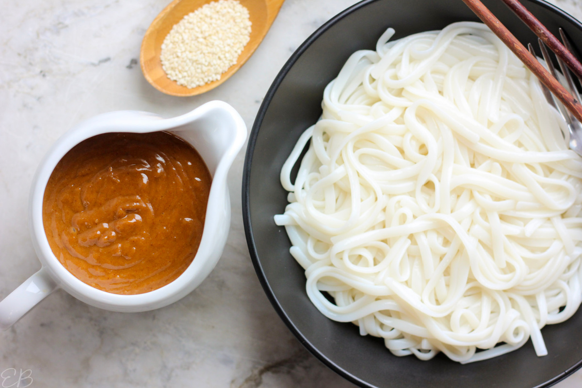 pitcher of paleo aip peanut butter sauce next to noodles