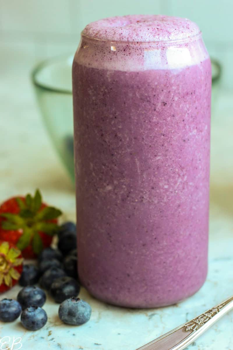 oatmeal banana berry smoothie in tall glass with fresh fruit on the side