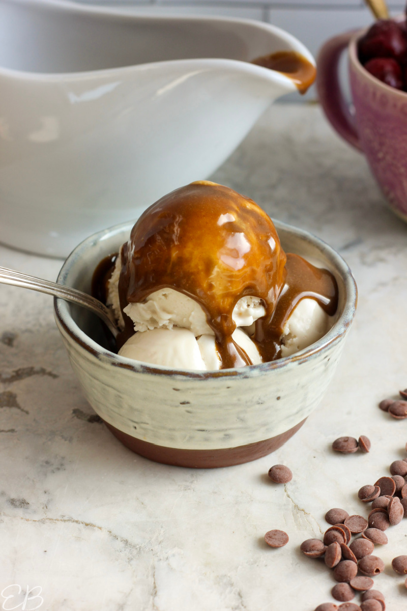 paleo vegan aip tiger nut dessert sauce poured over ice cream in bowl with spoon, with pitcher in background