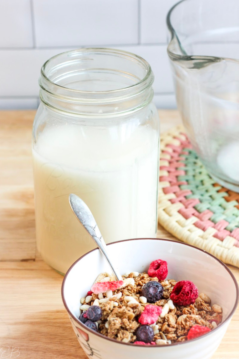 mason jar of oat milk with oat flour and cereal bowl in foreground