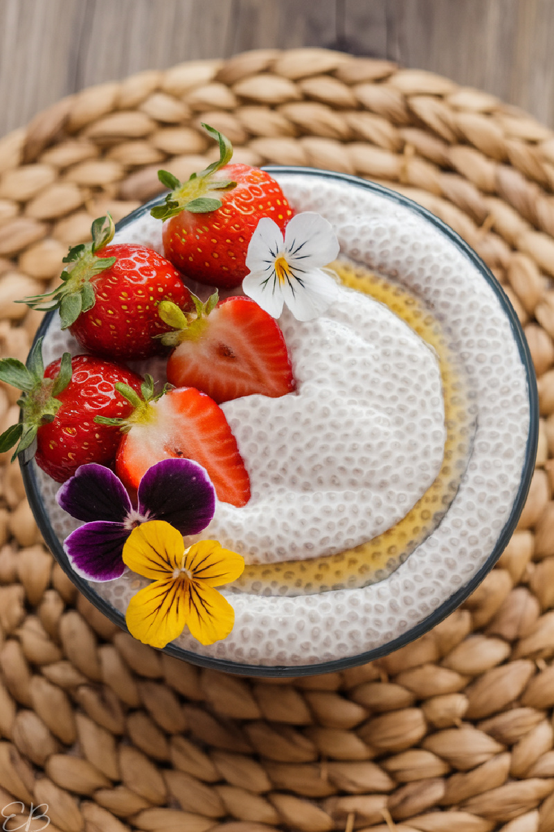 overhead view of strawberries and maple syrup, plus flowers, on simple 2 ingredient chia pudding