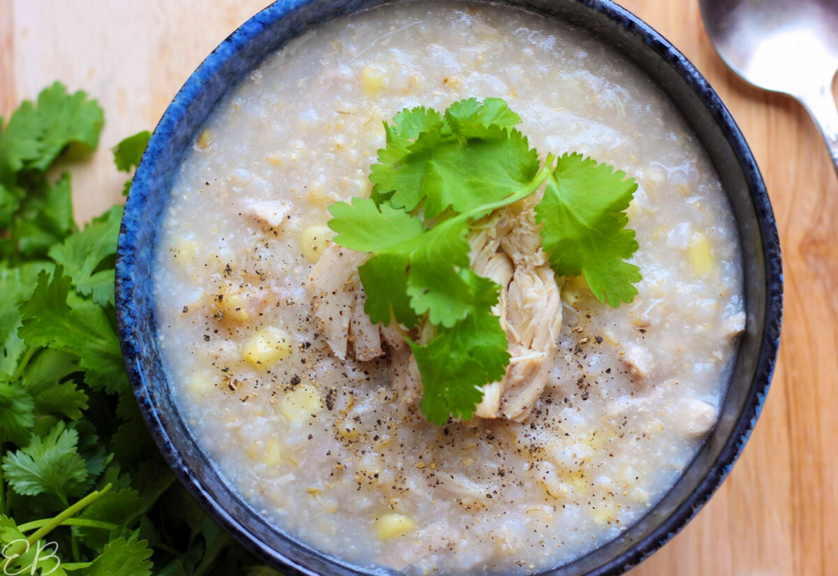 overhead view of congee served in dark bowl with condiments
