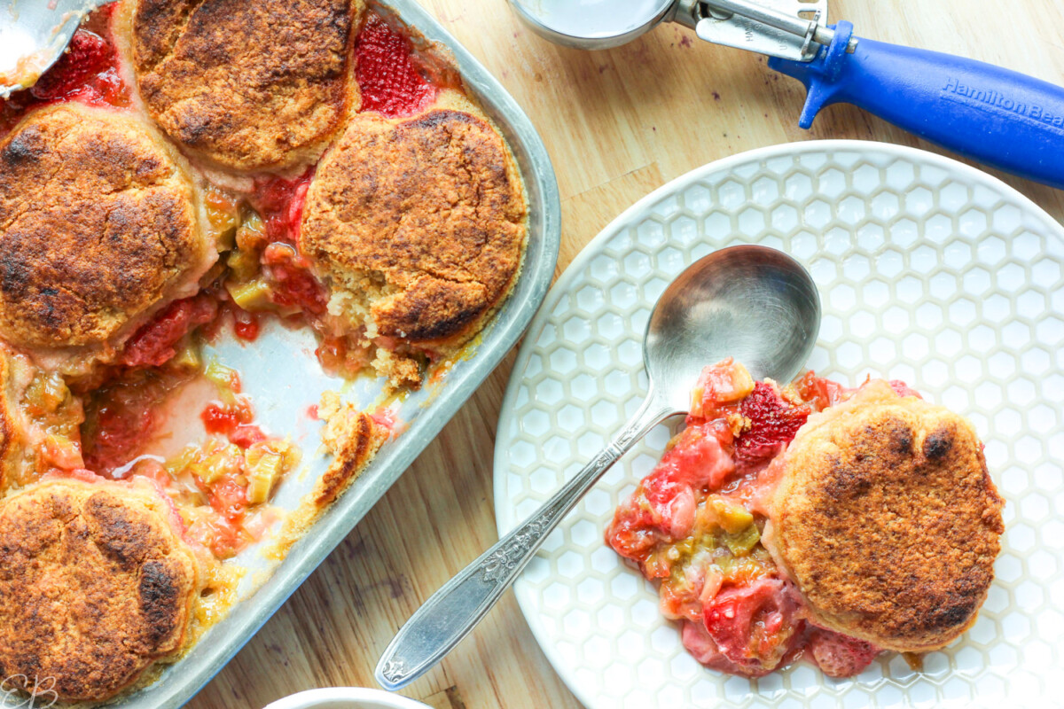 overhead view of served strawberry rhubarb cobbler, with one serving on white plate